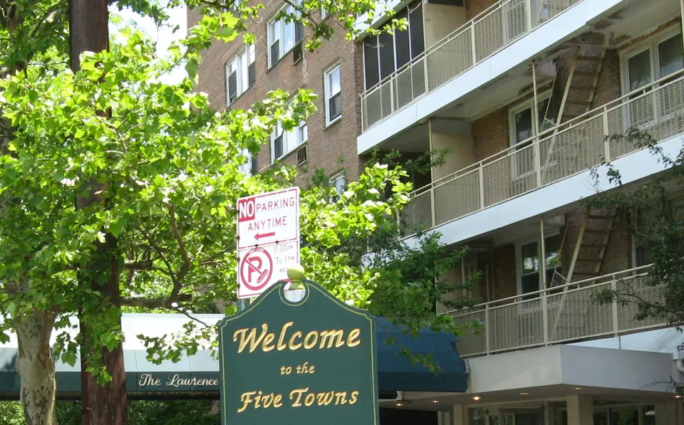 The Welcome to the Five Towns sign on a tree-lined street